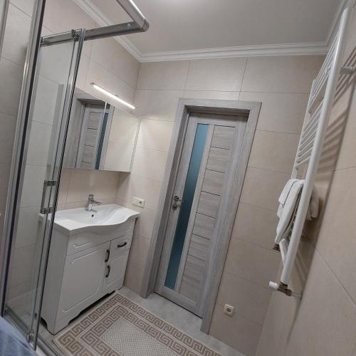 a white bathroom with a sink and a shower at Apartament lux new in Chişinău