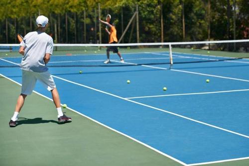 two men playing tennis on a tennis court at Knus chalet met zwembad en sauna in Sint Maartensvlotbrug