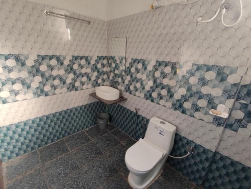 a bathroom with a toilet and blue and white tiles at Coral Beach Cottage in Māvalli
