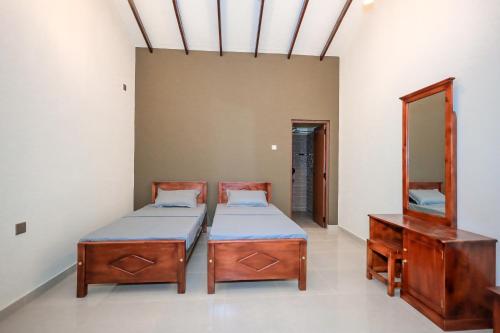 two beds in a room with a mirror and a dresser at Negombo 146 Homestay in Negombo