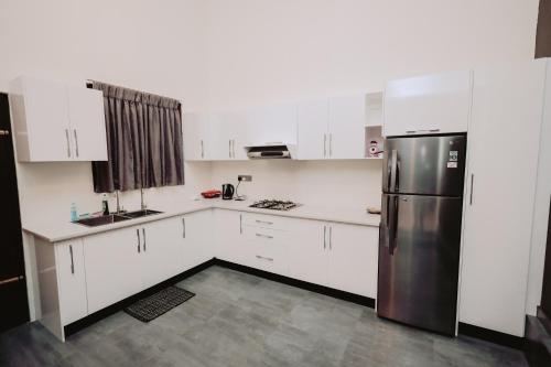 a kitchen with white cabinets and a stainless steel refrigerator at Negombo 146 Homestay in Negombo