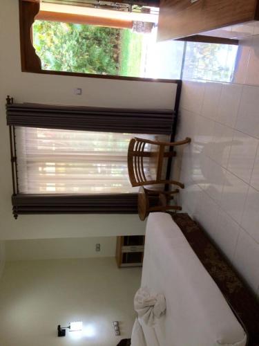 ein Schlafzimmer mit einem Fenster und einem Bett mit einem Stuhl in der Unterkunft Astina Hotel in Lovina