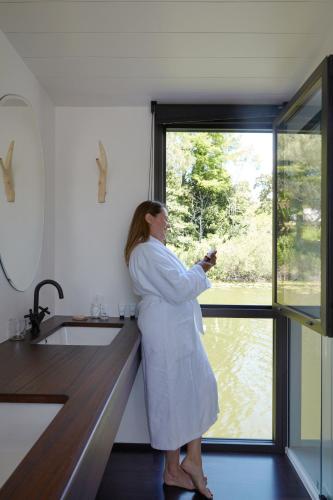 a woman standing in a kitchen looking out the window at Brindos, Lac & Château - Relais & Châteaux - Anglet Biarritz in Anglet