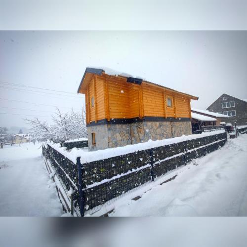 an orange building with a fence in the snow at Vila Helena in Kolašin