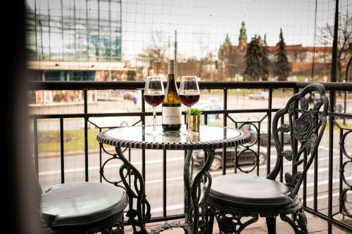 uma mesa com dois copos de vinho numa varanda em Luxe Living Castle View em Cracóvia