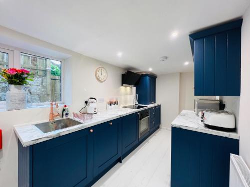 a large kitchen with blue cabinets and a sink at 20 Lisburn Street in Alnwick