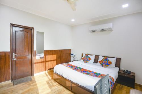 Schlafzimmer mit einem Bett und einer Holztür in der Unterkunft FabHotel Hexa Ghaziabad in Ghaziabad