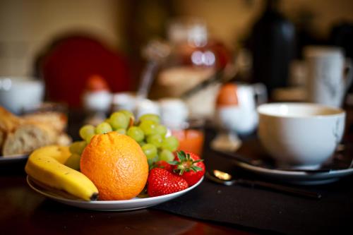 a bowl of fruit on a table with a plate of strawberries and bananas at Lodge ou Gîte de caractére avec jaccuzi spa piscine in Argelès-Gazost