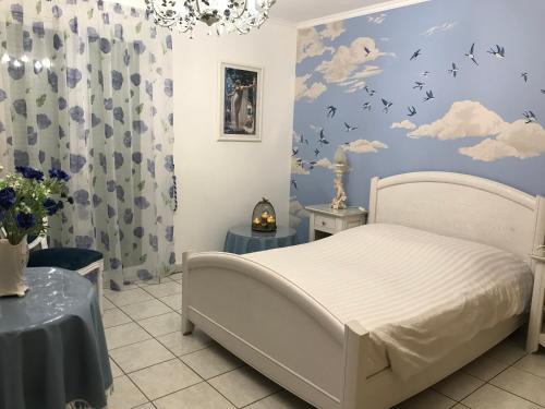 a bedroom with a bed with clouds and birds on the wall at Le chant des oiseaux - Au pied de la voie cyclable in Crévéchamps