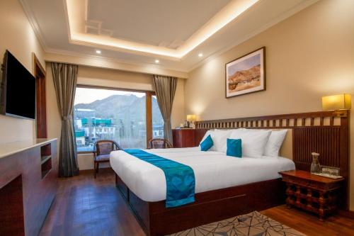a bedroom with a large bed and a large window at Ashoka Ladakh in Leh
