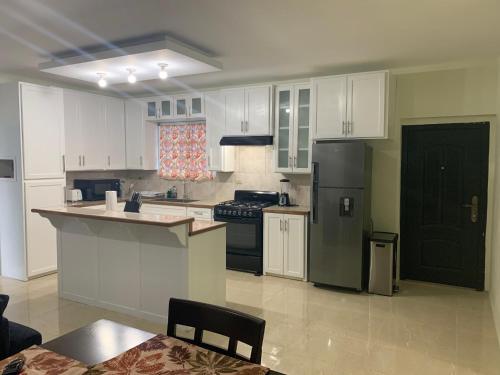 a kitchen with white cabinets and a black refrigerator at The Blue Moroccan Door - A modern 3 bedroom,2 bathroom home 