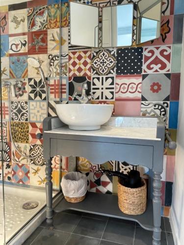 een badkamer met een wastafel en een muur bedekt met tegels bij Maison de charme avec imprenable vue mer, magnifique piscine et climatisation in Vallauris