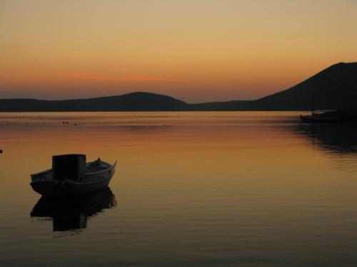 a boat sitting in the water at sunset at Marianna Studios in Aghios Petros Alonissos
