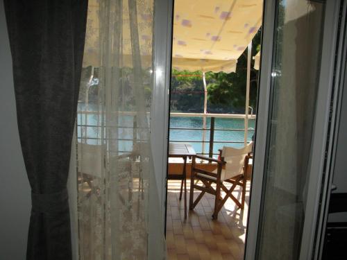 une porte coulissante en verre menant à une terrasse avec une table et des chaises. dans l'établissement Marianna Studios, à Aghios Petros Alonissos