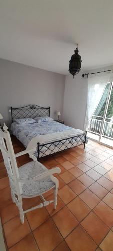 a bedroom with a bed and a chair and a window at chambres d'hôtes du capimont in Hérépian