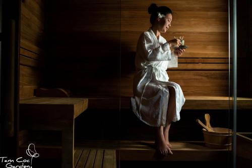 a woman sitting in a sauna looking at her cell phone at Tam Coc Garden Resort in Ninh Binh