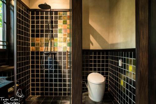 a bathroom with a toilet and a glass shower at Tam Coc Garden Resort in Ninh Binh