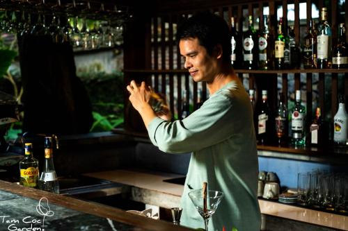 a woman standing at a bar preparing a drink at Tam Coc Garden Resort in Ninh Binh
