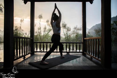 a woman doing a yoga pose on a porch at Tam Coc Garden Resort in Ninh Binh