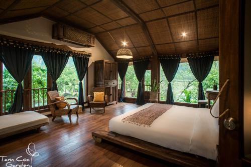 a bedroom with a large bed in a room with windows at Tam Coc Garden Resort in Ninh Binh