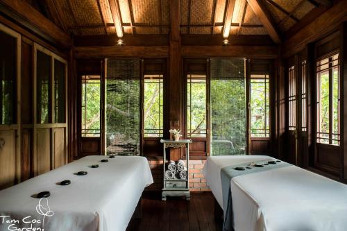 two beds sitting in a room with windows at Tam Coc Garden Resort in Ninh Binh