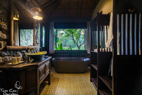 a bathroom with a tub and a large window at Tam Coc Garden Resort in Ninh Binh