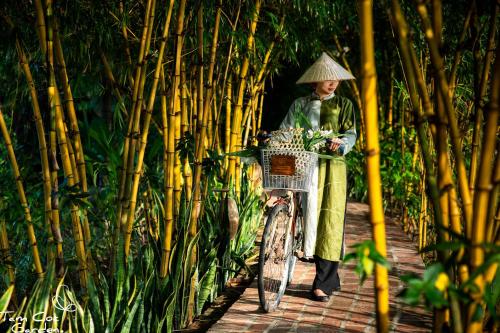 uma mulher ao lado de uma bicicleta com um cesto em Tam Coc Garden Resort em Ninh Binh