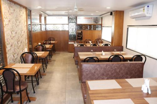 una sala da pranzo con tavoli e sedie in legno di Hotel Holiday Pride ad Aurangabad