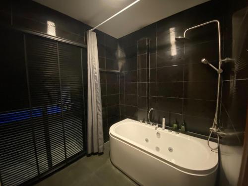 a bathroom with a white tub and black tiles at Maze Pool Villa Resort in Kamphaeng Phet