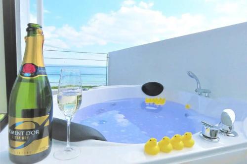 a bottle of champagne and a wine glass in a bath tub at BBQ無料 オーシャンビュー ジャグジー付1棟をまるまる貸切 2階建3LDK 無料駐車場4台 サファイアリゾートokinawa in Nanjo