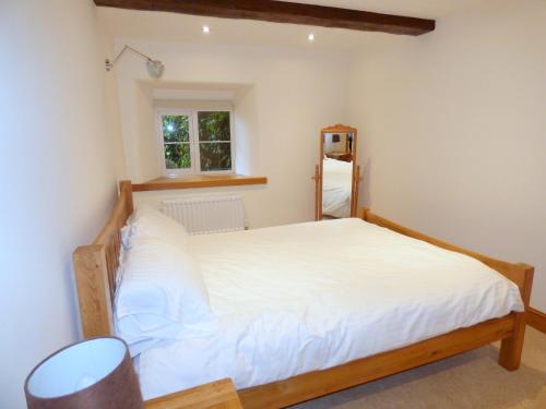 1 dormitorio con 1 cama con sábanas blancas y ventana en Great Barns en South Pool