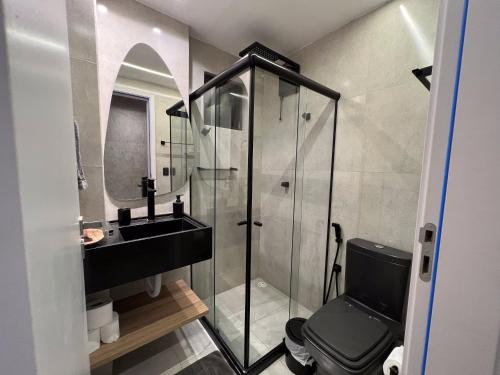 a bathroom with a glass shower and a black toilet at Housi, condo beira mar em Milagres in Passo de Camarajibe