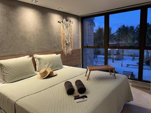 a bedroom with a bed with hats and flip flops on it at Housi, condo beira mar em Milagres in Passo de Camarajibe