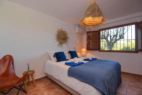 a bedroom with a bed and a chair and a window at Bogira in Jávea