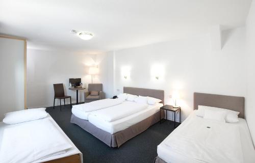 a hotel room with two beds and a desk at Hotel Klingelhöffer in Alsfeld