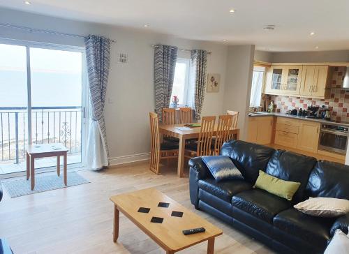 a living room with a black leather couch and a table at Ballycotton Holiday Apartment No 6 by Trident Holiday Homes in Ballycotton
