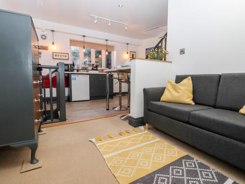 a living room with a black couch and a kitchen at Paddock View in Maidstone