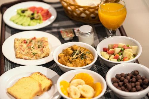 uma mesa com pratos de alimentos para o pequeno-almoço e um copo de sumo de laranja em La Maison Islamabad em Islamabad