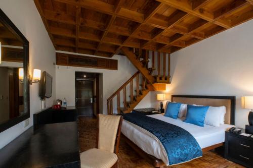 een slaapkamer met een groot bed en een trap bij Mastiff Grand Manali Resort in Manāli