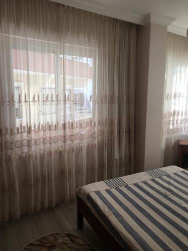a bedroom with a bed and a window with curtains at Cavide Hanım Apart in Didim