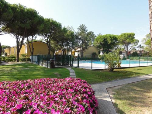 ogród z różowymi kwiatami i basenem w obiekcie Villaggio Azzurro Plus w Bibione