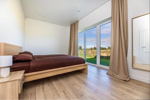 a bedroom with a bed and a large window at 360 Apartments in Užpelkiai