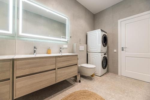 a bathroom with a washing machine and a washer and dryer at 360 Apartments in Užpelkiai