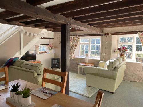 a living room with two couches and a table at Chiddy Nook Cottage in Chideock