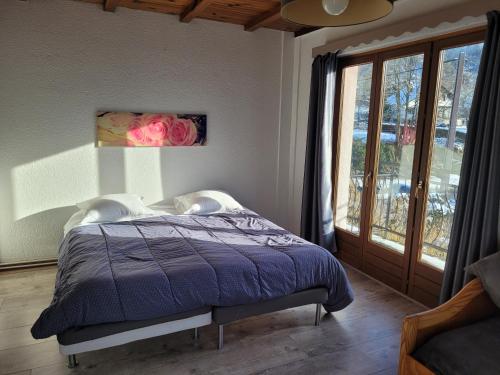 a bedroom with a bed with a purple comforter and a window at Les Jolis Coeurs in Thiéfosse