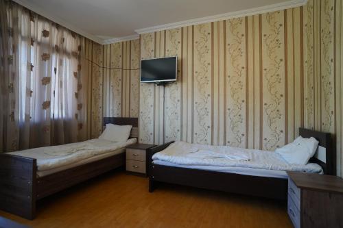 two beds in a room with a tv on the wall at imperator 1 Hotel in Kutaisi