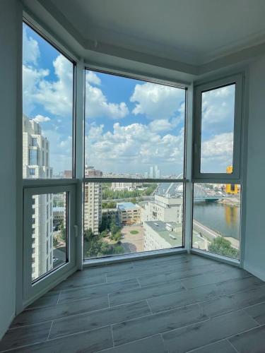 a room with large windows with a view of a city at Premium Apartments Esil Riverside in Astana