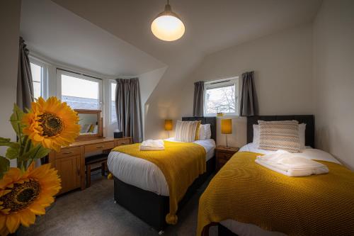 a bedroom with two beds and a desk with a mirror at Skyelight Apartment in Portree