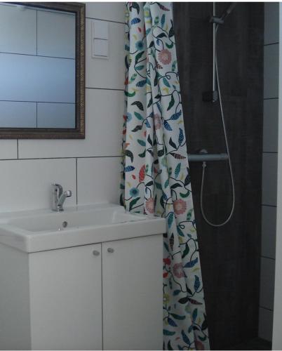 a bathroom with a sink and a shower curtain at Strandstudio Cato, vlakbij zee! in Callantsoog