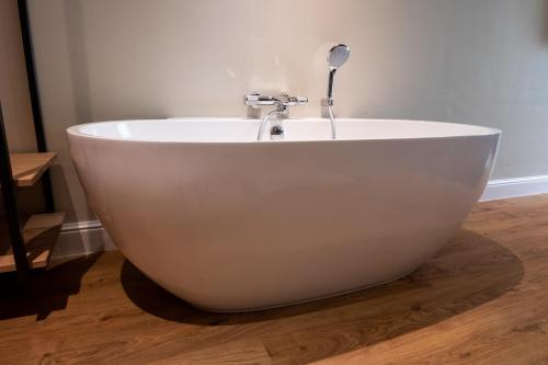 a white bath tub sitting on top of a wooden floor at Hotel Sanders de Paauw in Sluis
